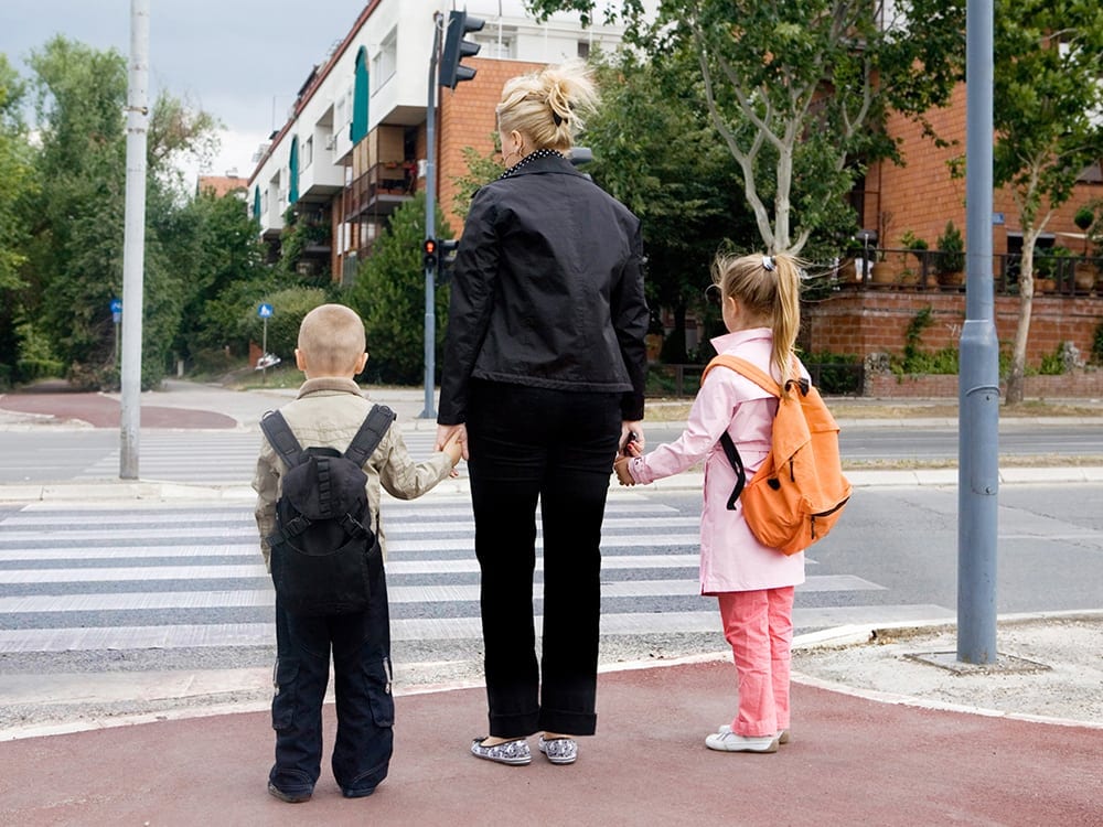mãe e filho atravessando a rua